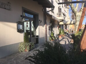 Un edificio con entrada empedrada en piedra, un letrero de metal y un pequeño árbol al frente.