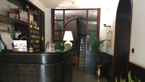 Un área de recepción con un mostrador de madera, una escalera y una planta en maceta.