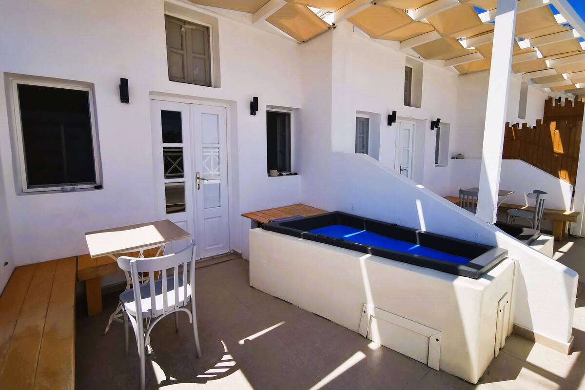 Une terrasse ensoleillée avec une table de billard, une table à manger et une chaise.