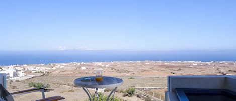 A balcony with a table, chairs, and a view of the sea.
