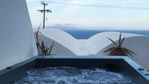 A hot tub with a view of the ocean and mountains. - Muses Cycladic Suites (Santorini)