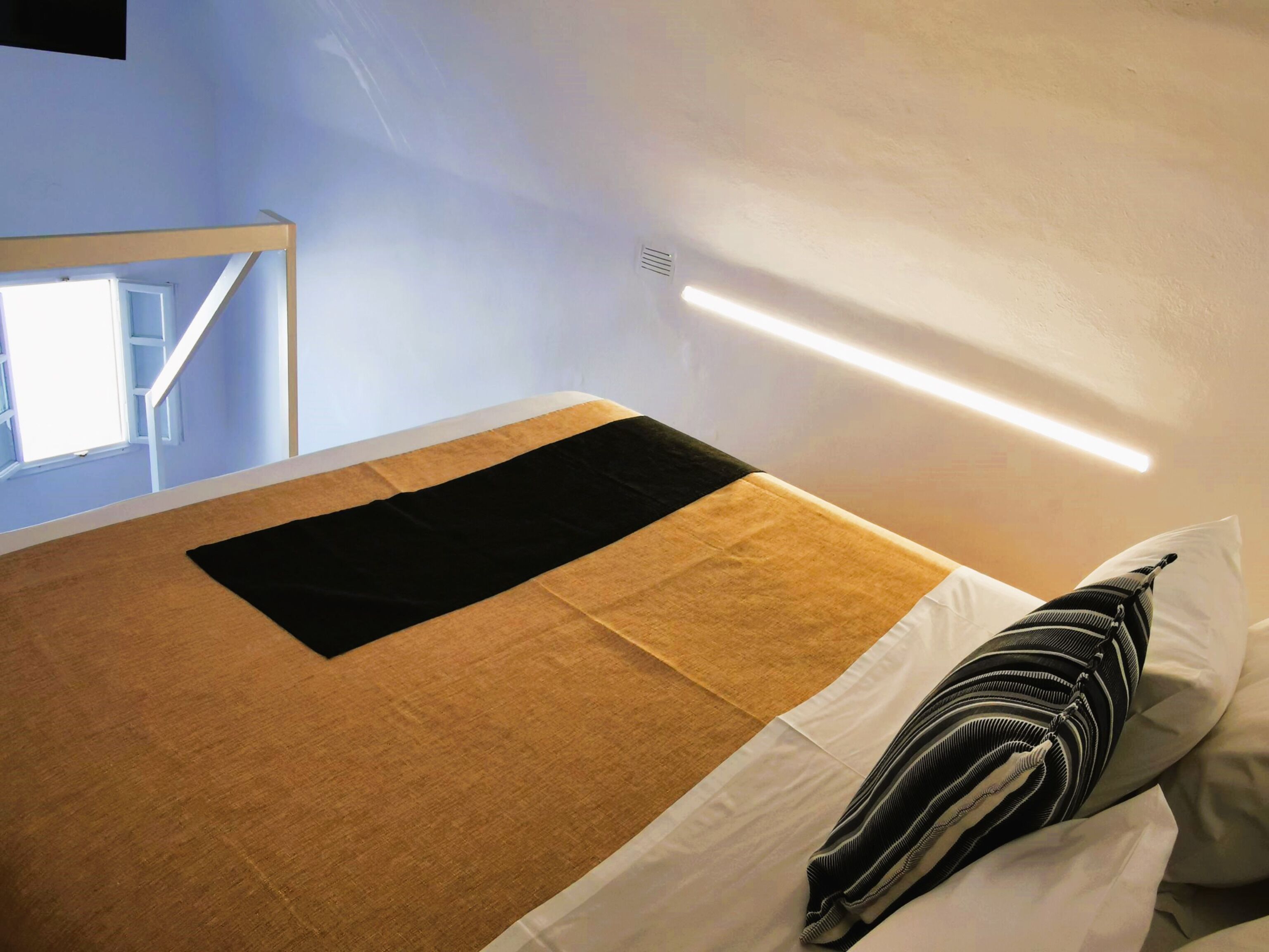 A bed with a black and beige bedspread, white pillows, and a striped pillow.