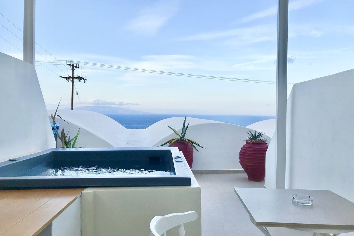 Un espace extérieur moderne, aménagé avec des sièges, une piscine, des plantes en pot et offrant une vue sur la mer.