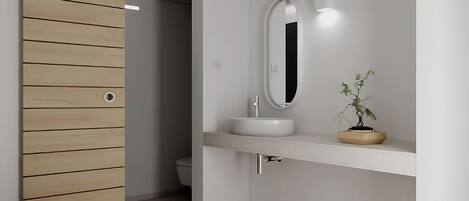 A modern bathroom with a wooden panel wall, a white sink with a round mirror, and a small potted plant.