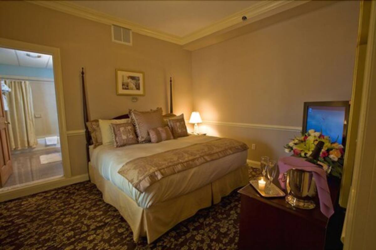 A hotel room with a bed, a nightstand with a lamp, a television, and a floral arrangement.