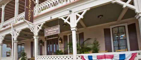 A two-story building with a balcony, a sign for 'La Verandah Restaurant', and a flag.