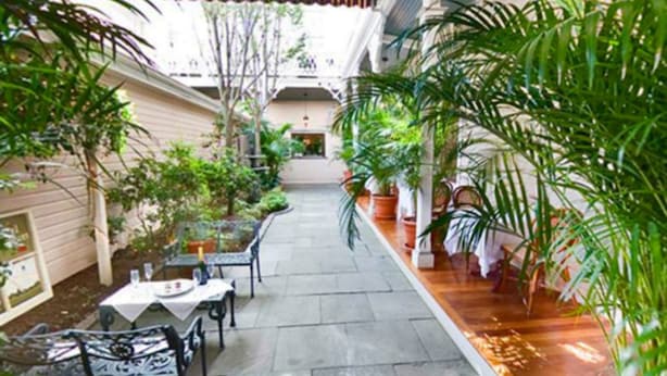 An indoor courtyard with a covered seating area, potted plants, and a central pathway. - Hotel Alcott (Cape May)