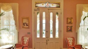 A room with a large double door, two chairs, a small table, and a patterned carpet. - Hotel Alcott (Cape May)