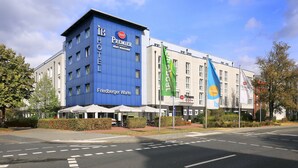 A hotel with a blue facade, a sign for 'Premier Best Western', and flags. - Best Western Premier IB Hotel Friedberger Warte (Frankfurt)