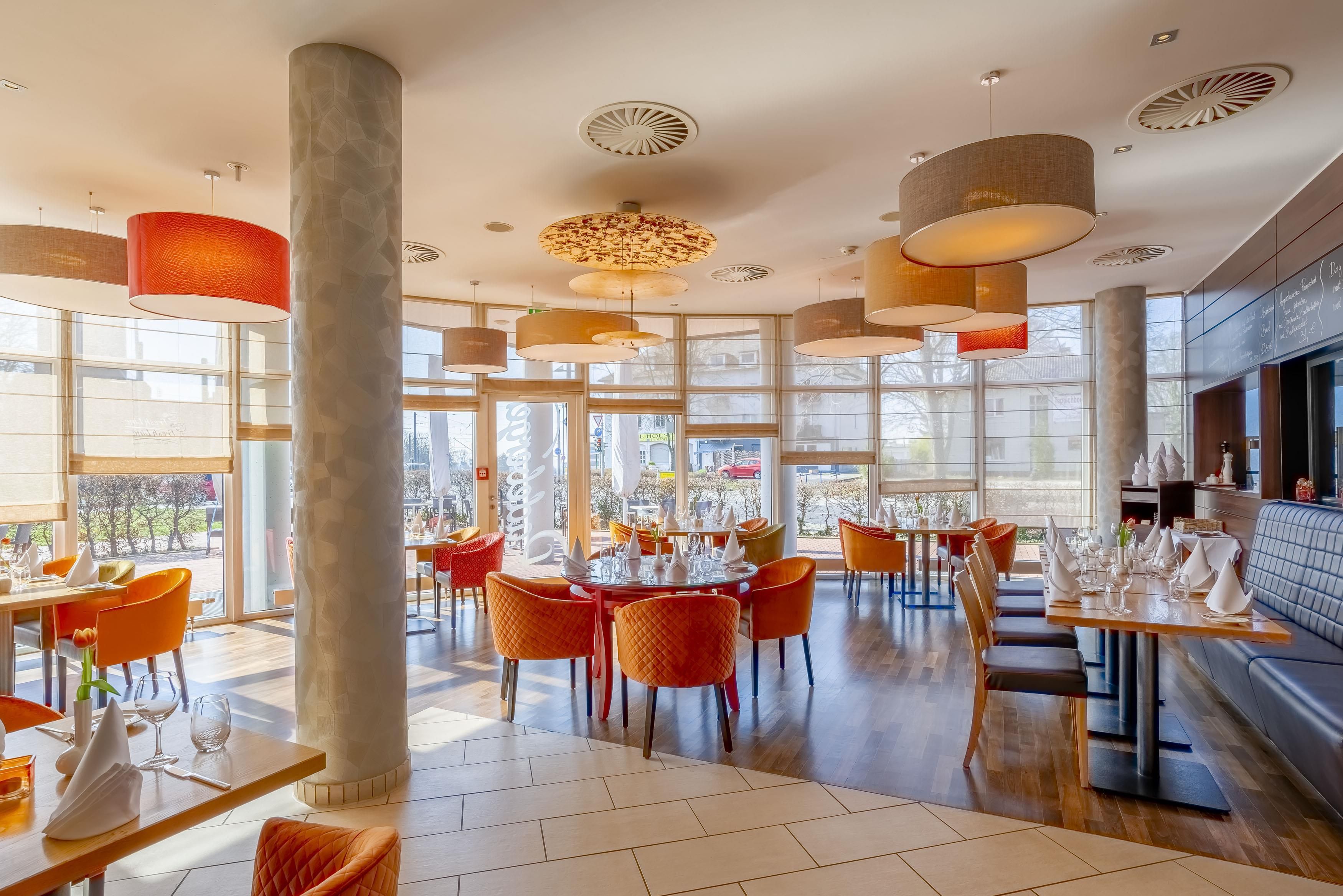A modern restaurant interior with high ceilings, large windows, and a variety of seating arrangements.