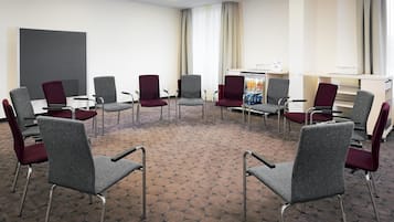 A conference room with a circular arrangement of chairs, a whiteboard, and a beverage cooler.