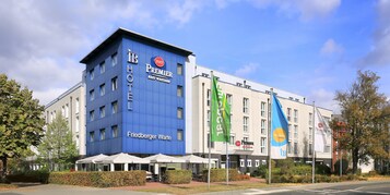 Un hotel con facciata blu, posti a sedere all'aperto e bandiere.