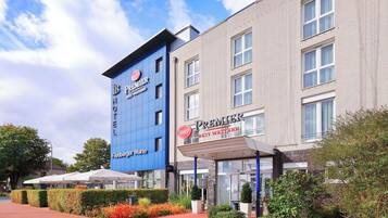 Experience the Premier Best Western's modern design, featuring a striking blue facade and classic brick details, with a welcoming entrance via covered walkway.
