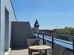 A balcony with a view of a tower, wicker furniture, and a railing. - Best Western Premier IB Hotel Friedberger Warte (Frankfurt)