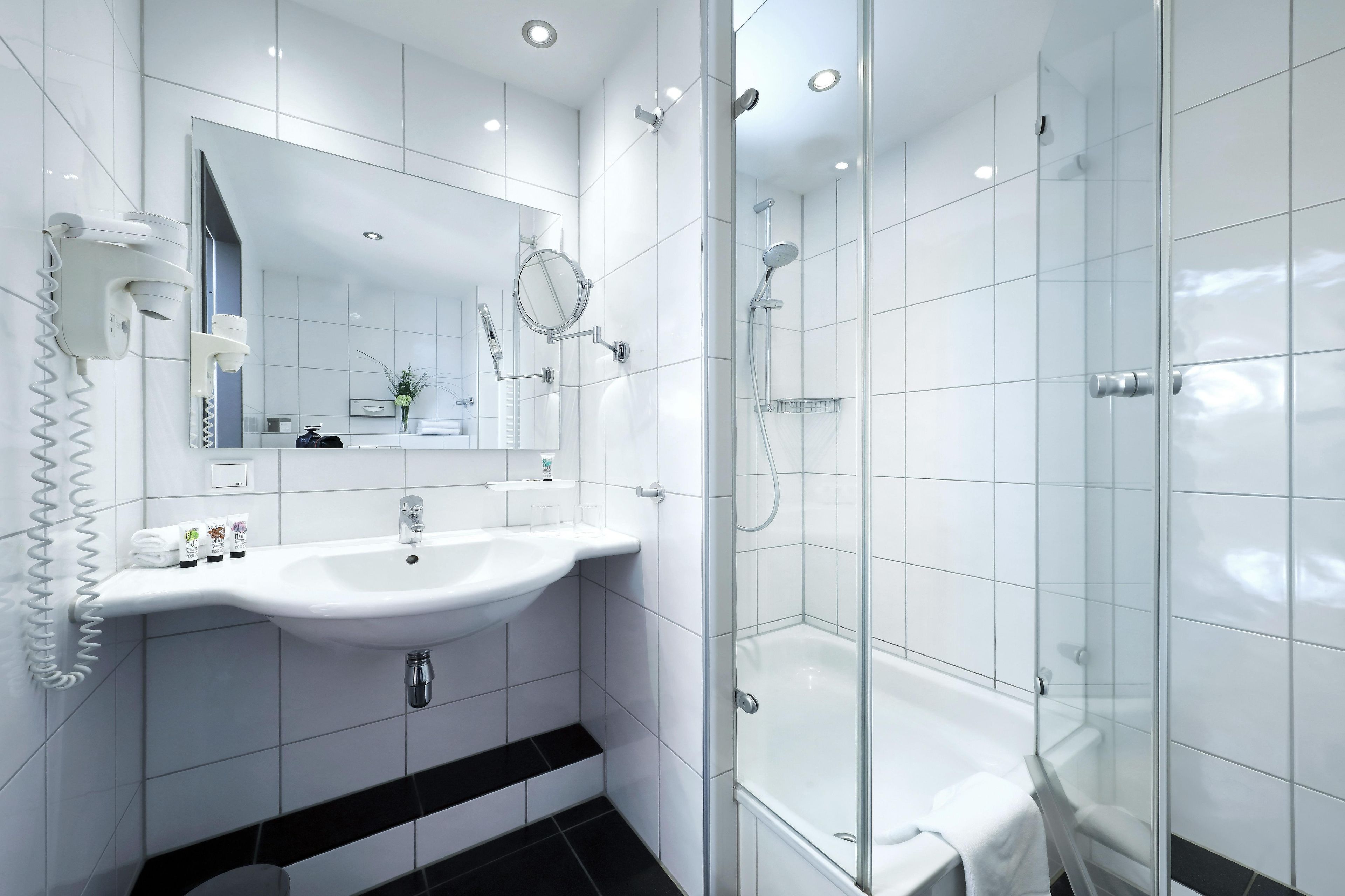 Une salle de bain moderne avec une douche à parois de verre, un lavabo blanc et un miroir.