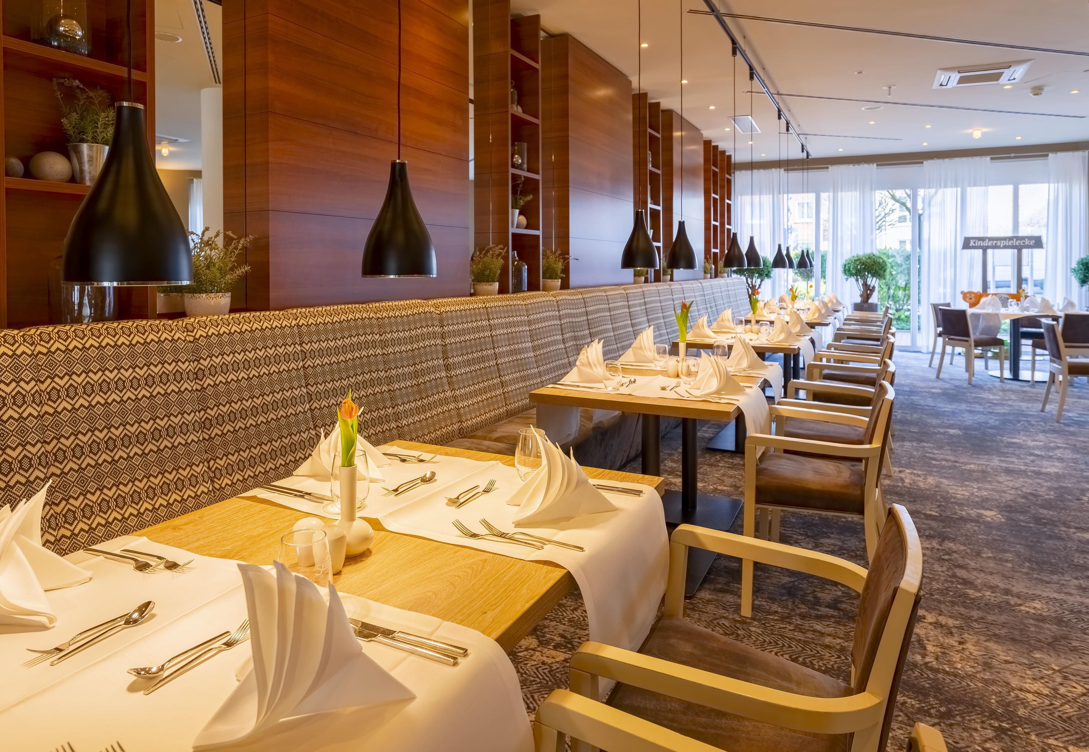 Un restaurant aux murs lambrés, doté d’un éclairage suspendu et d’un espace détente avec des bancs à motifs.
