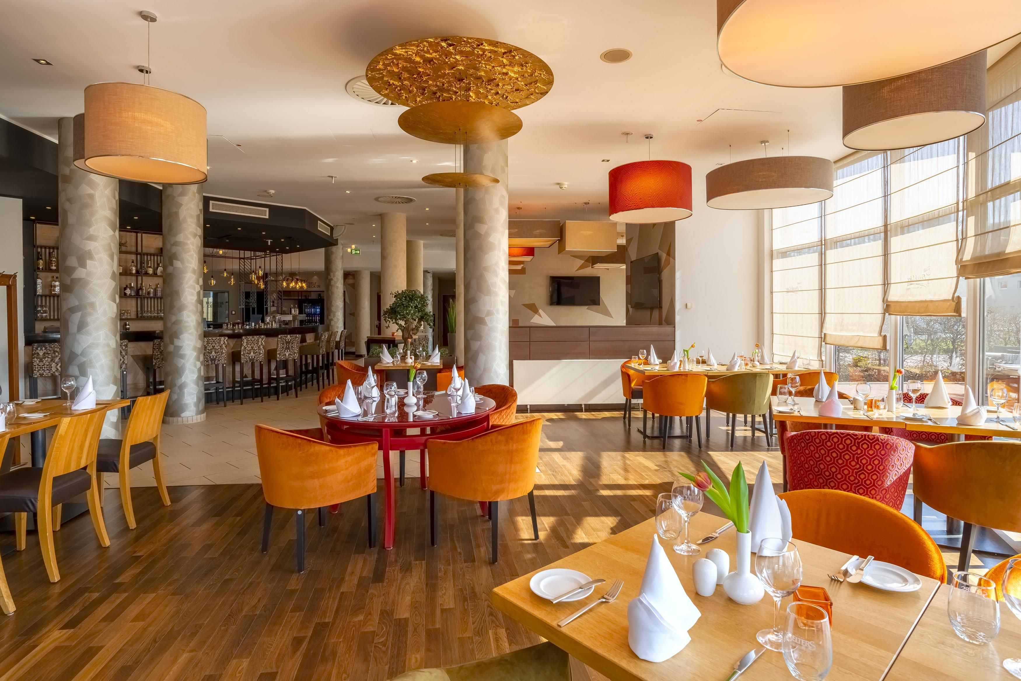 Interior moderno de restaurante com pé-direito alto, grandes janelas e diversos tipos de assentos.