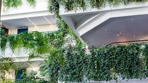Un atrio de varios niveles con abundante vegetación que se extiende por las paredes, una estructura de techo geométrica y un diseño arquitectónico moderno.