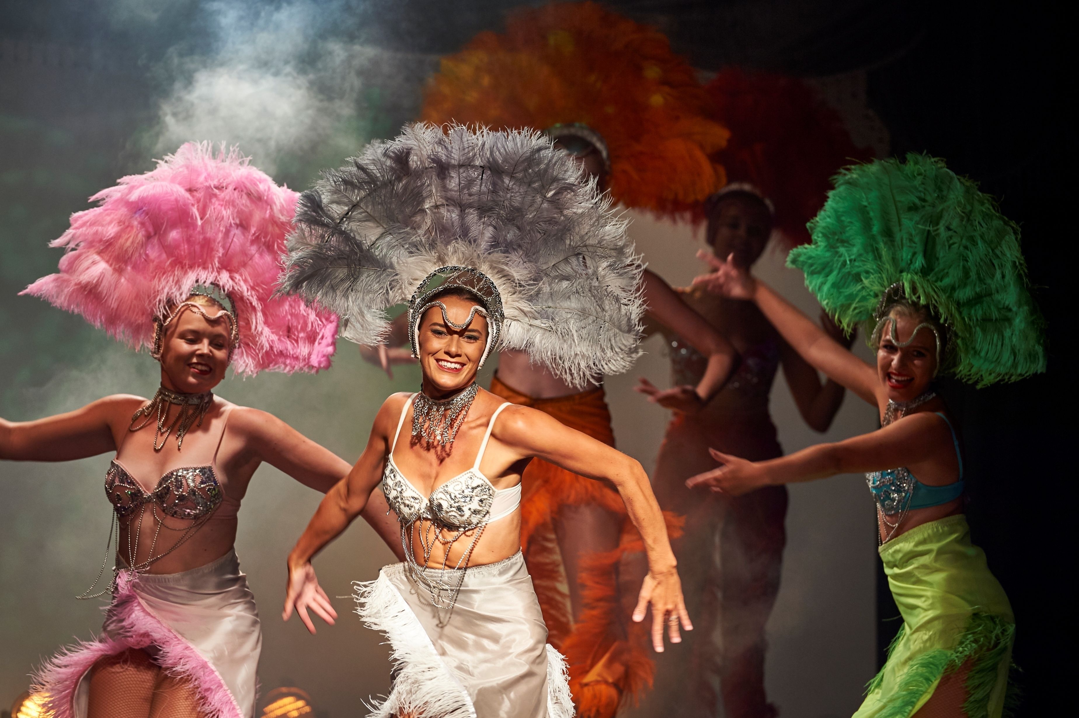 A group of dancers in colorful costumes with feathered headdresses.