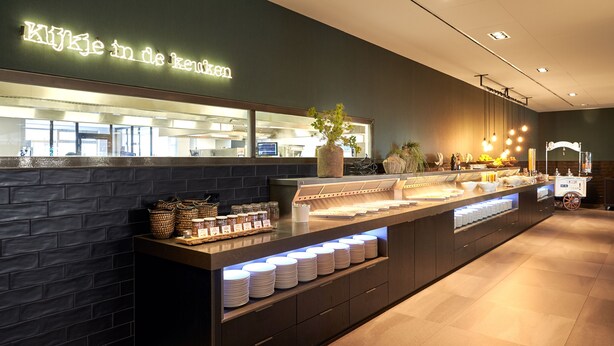 A buffet area with a dark brick wall, a neon sign, and a variety of food items displayed. - Van Der Valk Hotel Stein - Urmond (Urmond)