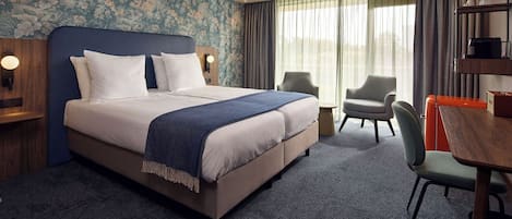 Une chambre d’hôtel avec un grand lit, un bureau, une chaise et une fenêtre avec des rideaux.