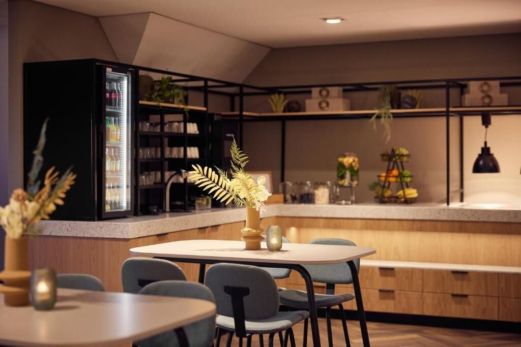 Una cocina moderna con refrigerador empotrado, un comedor con sillas y una barra con una planta.