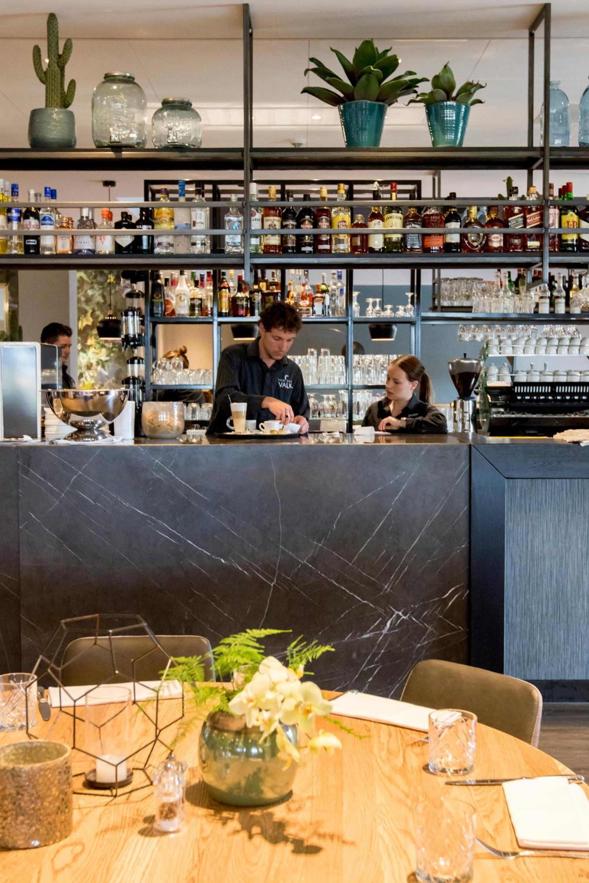 A bar area with a counter, shelves of liquor bottles, and a seating area with a table and chairs.