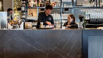 A bar area with a counter, shelves of liquor bottles, and a seating area with a table and chairs.