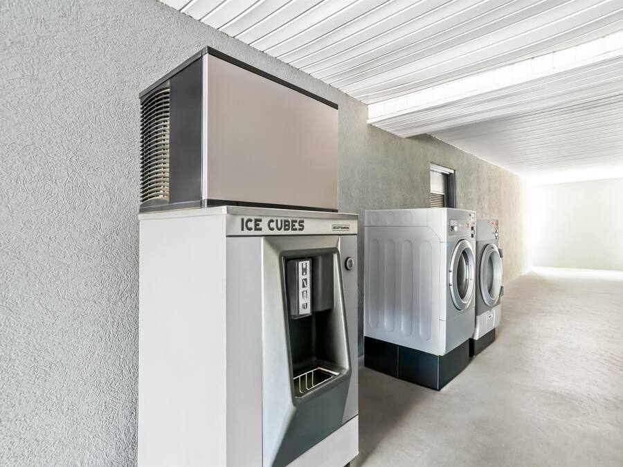 Una sala de lavandería con dispensador de hielo y lavadora de carga frontal.