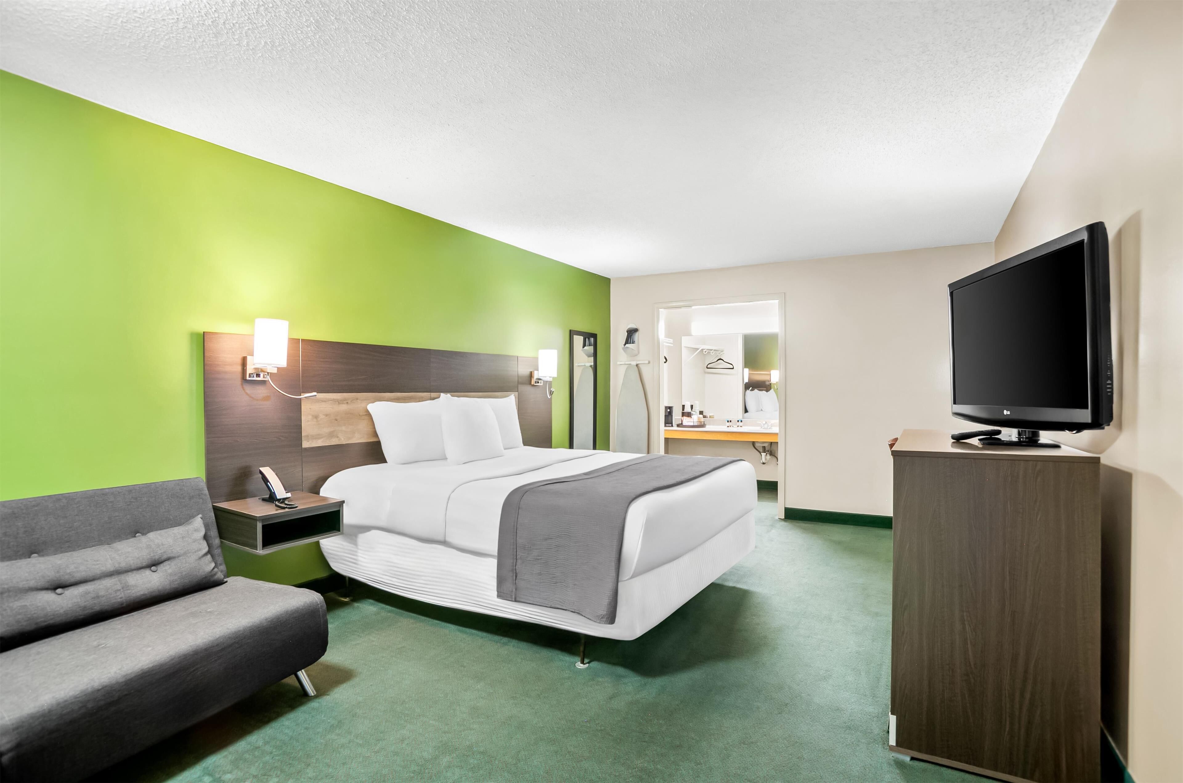 A hotel room with a bed, a TV, a desk, and a chair.