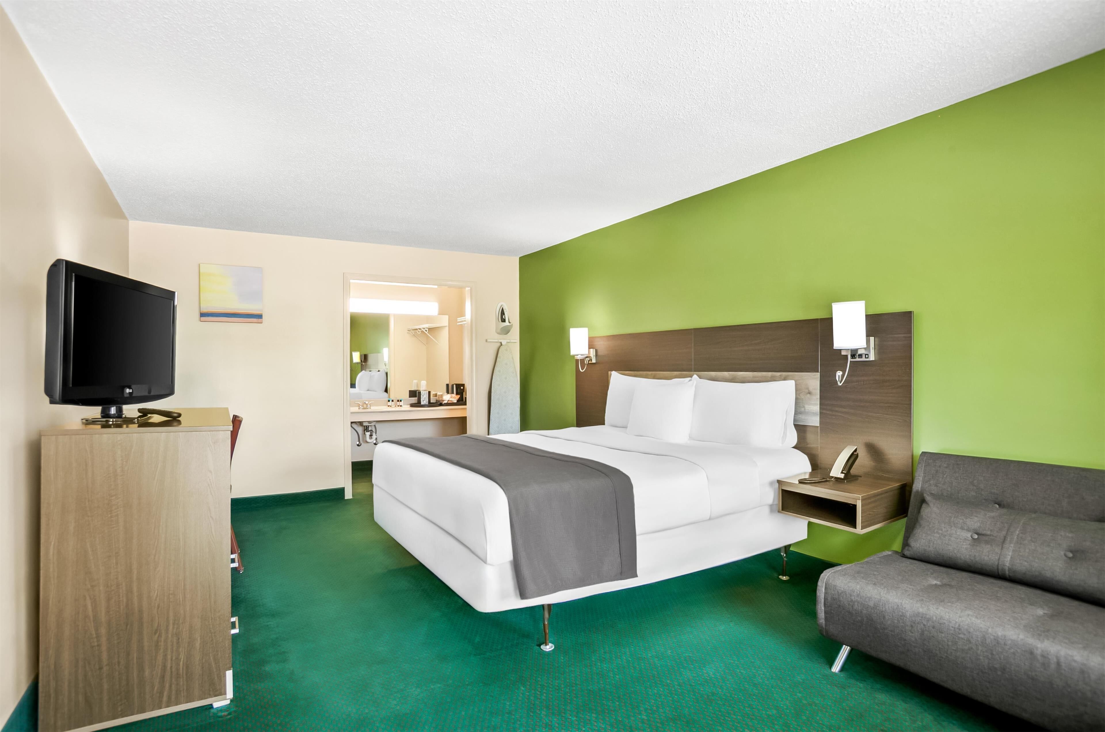 A hotel room with a bed, a TV, a desk, and a couch.