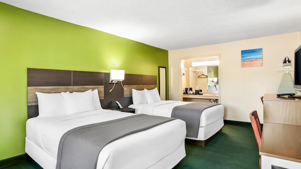 A hotel room with two beds, a desk, a chair, a mirror, and a small table with a lamp. - Americas Best Value Inn Rome (Rome)