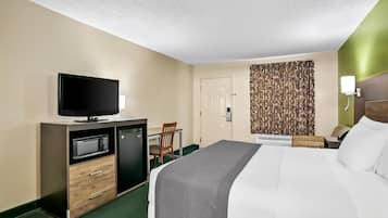 A hotel room with a bed, a TV, a microwave, a desk, and a chair.