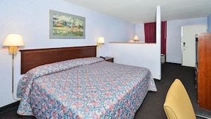 Een hotelkamer met een bed, twee bedlampen, een schilderij aan de muur, een deur en een televisietoestel.