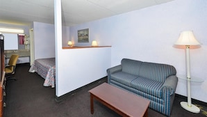 Een hotelkamer met een bank, een klein tafeltje, een lamp, een stoel en een bed.
