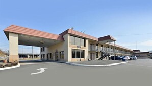 Een motel met een parkeerplaats, een overdekte doorgang en een gebouw met meerdere ramen en balkons.