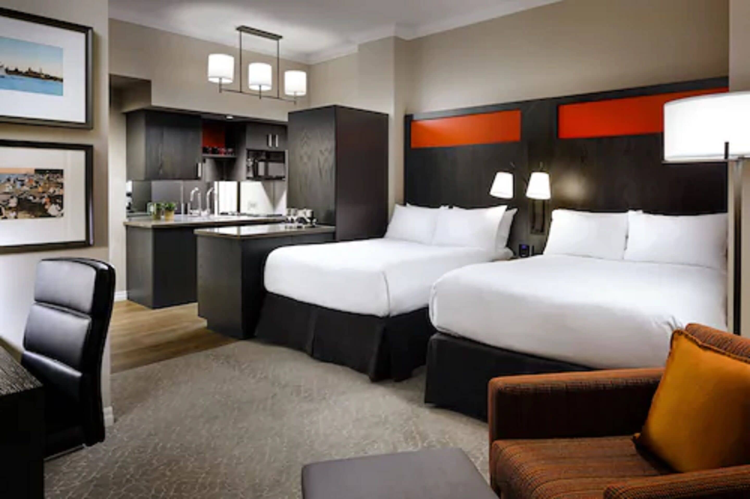 A hotel room with two beds, a desk, a chair, and a sofa.
