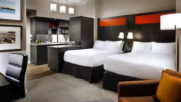 A hotel room with two beds, a desk, a chair, and a sofa.