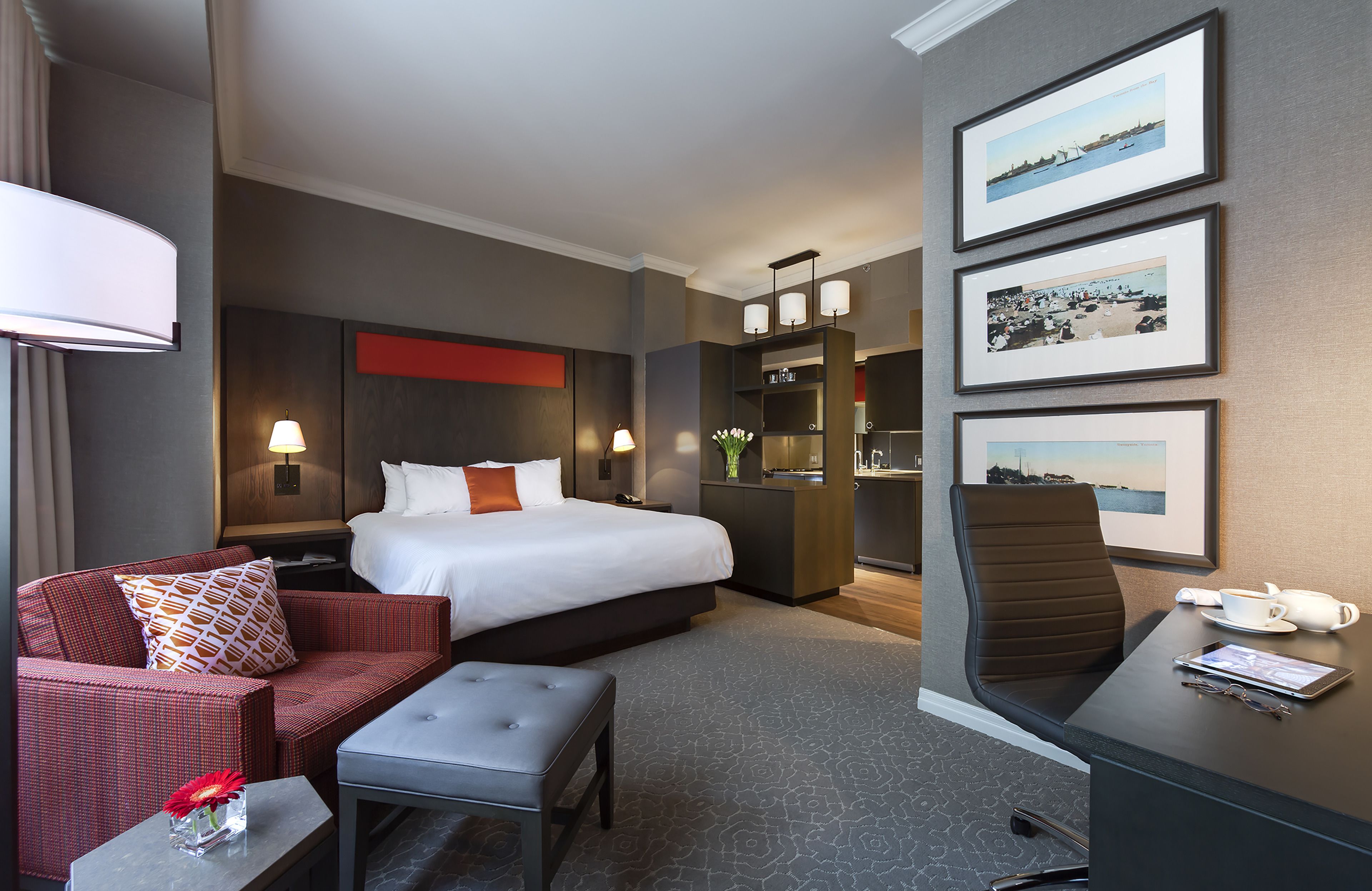 Een hotelkamer met een bed, een bureau, een stoel, een bank en een kleine tafel met een bloemenvaas.