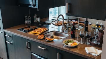 Una cocina moderna con un lavamanos de acero inoxidable, una botella de vino y un bol de ensalada.
