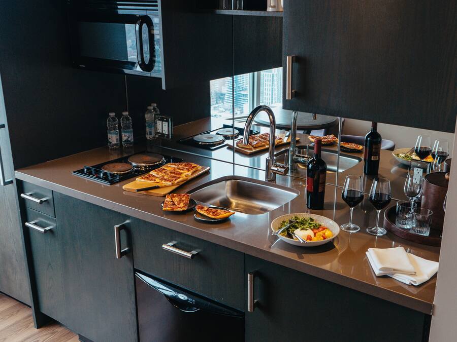 Una cocina moderna con un lavamanos de acero inoxidable, una botella de vino y un bol de ensalada.