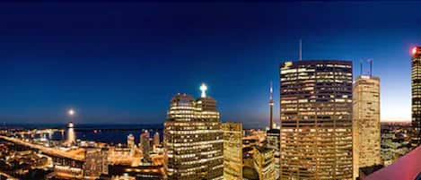 A city skyline at night with illuminated buildings and a body of water in the background.