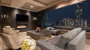 A modern living room with a fireplace, comfortable seating, and a large TV. - One King West Hotel & Residence (Toronto)