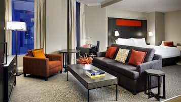 Una habitación de hotel con una cama, un sofá, una mesita de centro, una silla y una pequeña mesa.