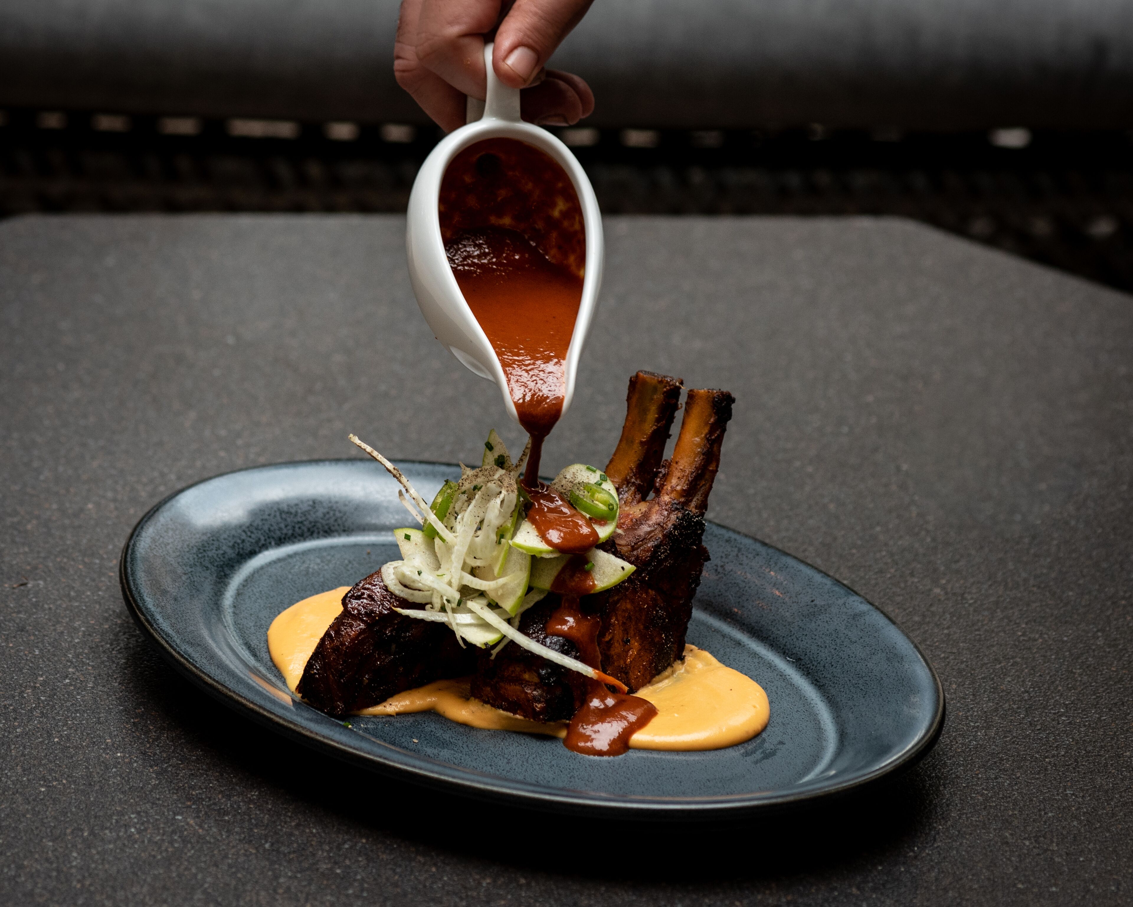 A plate of ribs with sauce and garnishes.