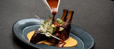 A plate of ribs with sauce and garnishes.