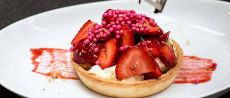 A dessert on a plate with strawberries and berries, and a hand grating something on top.