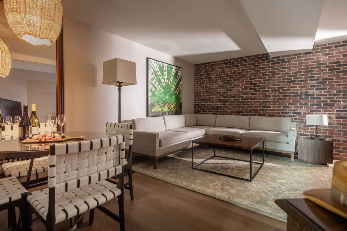 Un salon moderne avec un canapé d’angle, une table basse et un coin repas comprenant des chaises et une table mise pour le repas.
