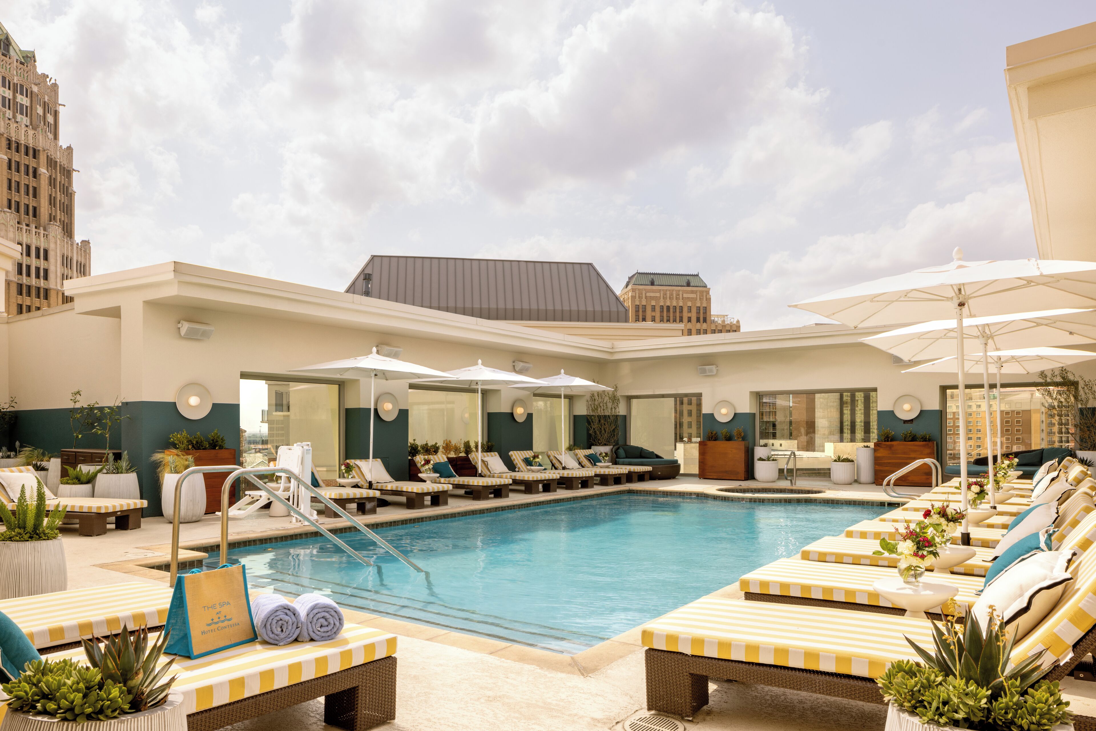 Área de piscina no terraço com espreguiçadeiras, guarda-sóis e uma placa indicando 'The Spa'.