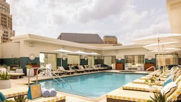 A rooftop pool area with lounge chairs, umbrellas, and a sign indicating 'The Spa'.